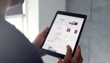 Männliche Hand stöbert in einem Online-Shop auf einem digitalen Tablet, das Schuhe verkauft
